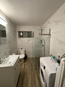 a bathroom with a shower toilet and a washing machine at kasa or in Herzelia 