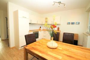 ヴィーク・アウフ・リューゲンにあるFerienwohnung Wiek im Hafenkiekerのキッチン(花瓶付きの木製テーブル付) +36枚の写真
