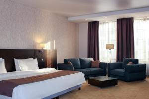 um quarto de hotel com uma cama e duas cadeiras em Solutel Hotel em Bishkek