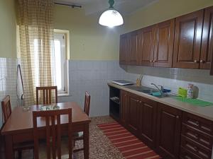 a kitchen with wooden cabinets and a table and a sink at La Casetta della fontana del muro in San Lorenzo Nuovo