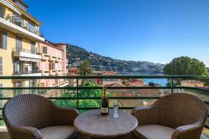Una botella de vino sentada en una mesa en un balcón en Appartement d Exception, Spacieux et Lumineux, avec Balcon et Vue Mer, en Villefranche-sur-Mer