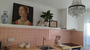 a kitchen with a sink and a painting of a woman at Casa Buganvilia Penela - rooms near of the castle in Penela +53 photos