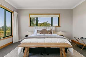 a bedroom with a large bed and a wooden bench at Spacious 5-Star Home with Pool in Taupo +48 photos