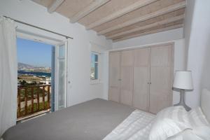 a white bedroom with a bed and a balcony at Villa Pearl near Ornos by Diles Villas in Agios Ioannis Mykonos