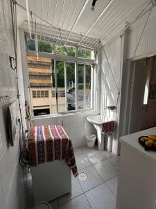 une petite salle de bain avec un lavabo et une fenêtre dans l'établissement Apartamento Pé na Areia Guarujá Pitangueiras, à Guarujá
