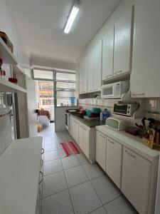 Il comprend une cuisine avec des placards blancs et du carrelage blanc. dans l'établissement Apartamento Pé na Areia Guarujá Pitangueiras, à Guarujá 15 autres photos