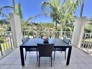 a blue table and chairs on a balcony with palm trees at Peppers Salt Resort & Spa 2 br luxury spa suite in Kingscliff
