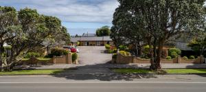 a street in a residential neighborhood with a fence and trees at ASURE Highpark Motor Inn in Greymouth