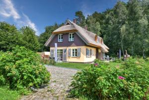una pequeña casa amarilla con techo de paja en Ferienhaus Inselliebe 02 Feriendorf Klein Stresow Rügen by ruyastay, en Putbus