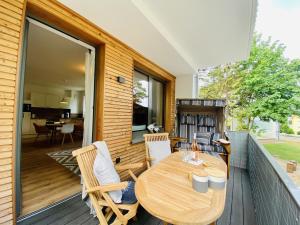 a porch with a wooden table and chairs on a deck at Ferienwohnung Strandkorb & Mee h r Parkvillen Carlota und Candela Baabe in Baabe