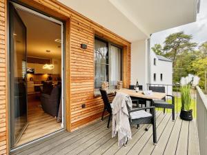 Un patio con una mesa y sillas en una terraza. en Ferienwohnung Morgensonne Parkvillen Carlota und Candela Baabe, en Baabe