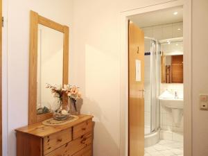 ein Badezimmer mit einer Blumenvase auf einer Kommode mit Spiegel in der Unterkunft Freundliches 2-Zimmer-Appartement mit Kieferneinrichtung und einem Balkon. in Westerland + 10 Fotos