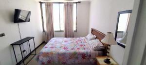 a bedroom with a bed and a lamp and a window at Dpto Calama Centro in Calama +5 photos
