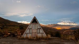 a small house with mountains in the background at Illamama in La Paz