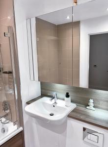 a white bathroom with a sink and a mirror at Luxury 2-Bedroom London Apartment, 25mins to Liverpool Street, Balcony, Free Parking in London +27 photos