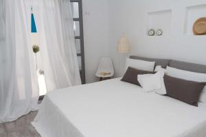 a white bedroom with a large white bed with pillows at Enosis Apartments - Alia Beach House in Agios Prokopios