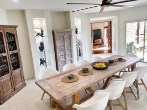 a dining room with a wooden table and white chairs at Emerald Beach Lakefront Luxury Mansion in Emerald Beach