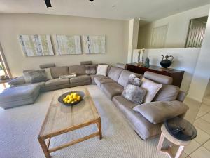 a living room with a couch and a table at Emerald Beach Lakefront Luxury Mansion in Emerald Beach