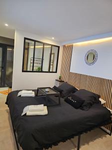 a bedroom with two beds with black sheets and a table at Appartement SPA - Lovers Suite in Clermont-lʼHérault