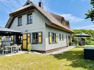 Ferienhaus Huus Waterkant 18 Feriendorf Klein Stresow Rügen by ruyastay في بوتبوس: كوخ بسقف من القش مع فناء