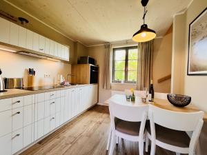a kitchen with a white table and white cabinets at Ferienhaus Boddenblick 15 Feriendorf Klein Stresow Rügen by ruyastay in Putbus