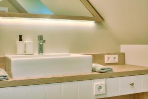 a bathroom with a white sink and a mirror at Ferienhaus Große Lage 16 Feriendorf Klein Stresow Rügen by ruyastay in Putbus +12 photos