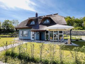 a house with a thatched roof with an umbrella at Ferienhaus Boddenlust 24 Feriendorf Klein Stresow Rügen by ruyastay in Putbus