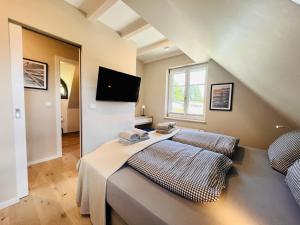 Ferienhaus Boddenlust 24 Feriendorf Klein Stresow Rügen by ruyastay في بوتبوس: غرفة نوم بسريرين وتلفزيون على الحائط