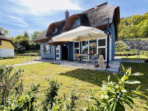 Ferienhaus Boddenlust 24 Feriendorf Klein Stresow Rügen by ruyastay في بوتبوس: منزل مع فناء مع مظلة