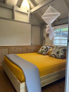 a bedroom with a yellow bed in a room at KER MARYA Bungalow in Terre-de-Haut