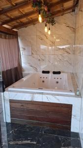 a bath tub in a bathroom with a marble wall at Sítio Ramos casa azul in Cunha