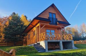 a log cabin with a porch and a deck at Domek na Czerwonej Górce in Uście Gorlickie