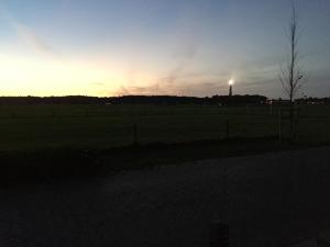 a sunset in a field with a water tower in the background at Amelander Kaap Appartement 112 in Hollum