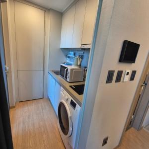 una pequeña cocina con lavadora y microondas en Elbons, en Busan