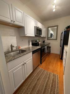 a kitchen with white cabinets and a sink at Sun-filled 1b 1ba W City Views Near Public Trans in Boston +3 photos