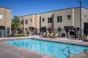 Una piscina con sillas frente a un edificio. en Downtown Moab Basecamp Pool & Hot Tub - Entrada, en Moab