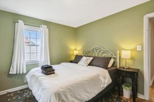 a bedroom with a bed with green walls and a window at The Henry House I Pet Friendly Cozy Convenient in Fairview Park