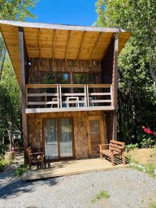 a wooden cabin with a deck and two chairs at K m 6 River Lodge in Pucón