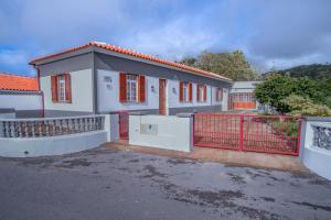 ein Haus mit einem roten Tor davor in der Unterkunft Vivenda Graciosa in Boa Hora