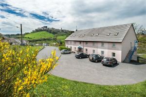 a group of cars parked in a driveway next to a building at Brit Hotel Essentiel Saint-Flour in Saint-Flour