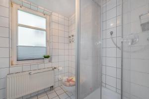 ツィノヴィッツにあるDünenresidenz 10の白いタイル張りのバスルーム(シャワー、窓付) +8枚の写真