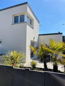 a white house with palm trees in front of it at Jacuzzi & Sauna privatifs - Vue mer in Blainville-sur-Mer