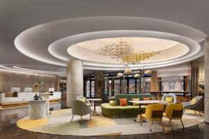 a lobby with a green couch and tables and chairs at Home2 Suite by Hilton Harbin Central Street in Harbin