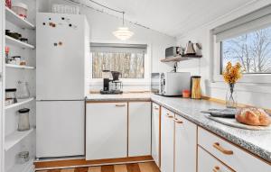 a kitchen with white cabinets and a white refrigerator at 2 Bedroom Lovely Home In Almind in Almind