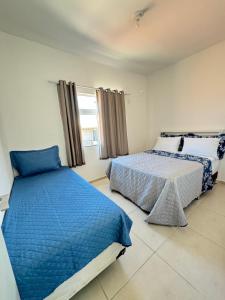 a bedroom with two beds and a window at Casa brisa do mar 2 in Arraial do Cabo