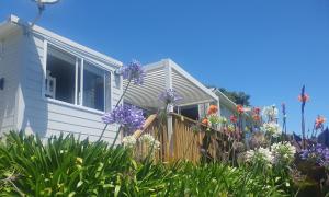 a house with flowers in front of it at Stanmore Bay Beach House in Whangaparaoa