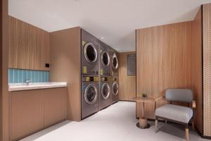a laundry room with four washing machines and a sink at Home2 Suite by Hilton Harbin Central Street in Harbin