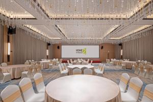 a banquet hall with white tables and chairs and a projection screen at Home2 Suite by Hilton Harbin Central Street in Harbin