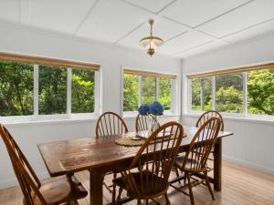 a dining room with a table and chairs and windows at Westlee Cottage in Wentworth Falls +14 photos