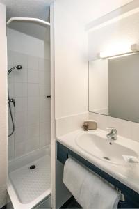 a bathroom with a sink and a shower and a mirror at Brit Hotel Essentiel Saint-Flour in Saint-Flour